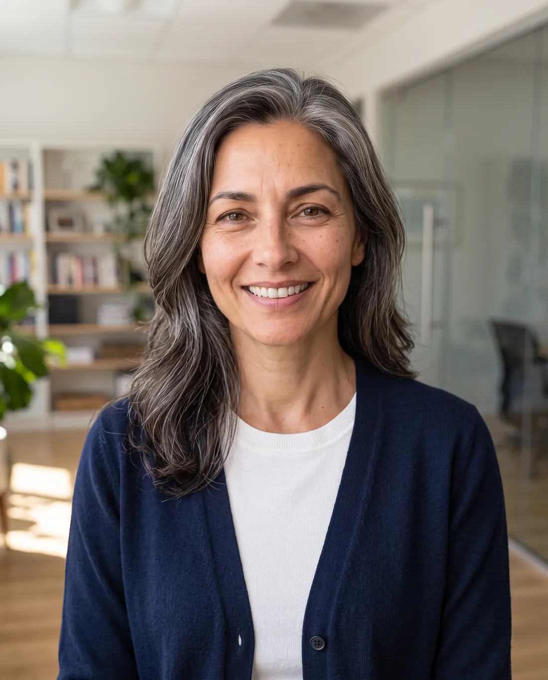 Business casual headshot in a navy cardigan, bright office background