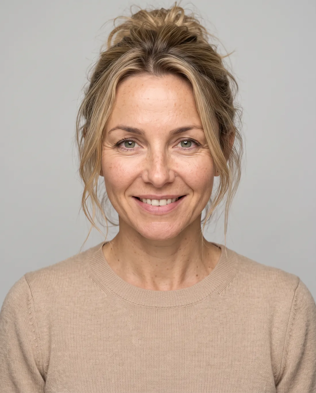 Headshot in a beige knit sweater, neutral studio backdrop
